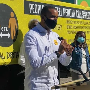 Josh Harris, black man in a mask standing at podium