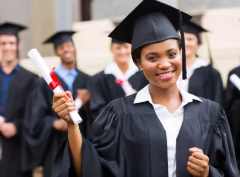 Smiling Female Graduate Wearing Cap and Gown Holding Diploma